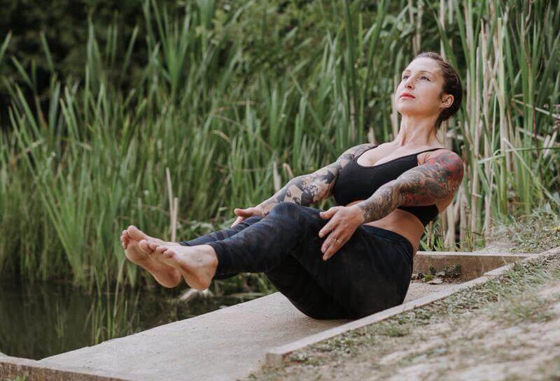 Mulher fazendo a postura de yoga Navasana